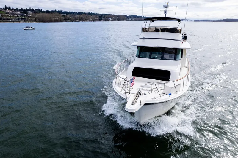 Slide: The Image of 1986 Hatteras 63 Motor Yacht cruising on a calm lake under a cloudy sky. - 159