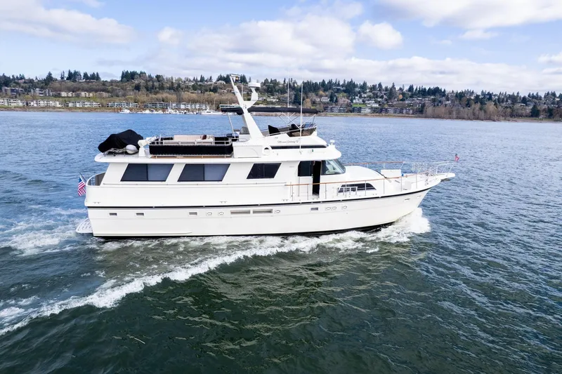 Slide: The Image of 1986 Hatteras 63 Motor Yacht cruising on a scenic lake under a partly cloudy sky. - 161