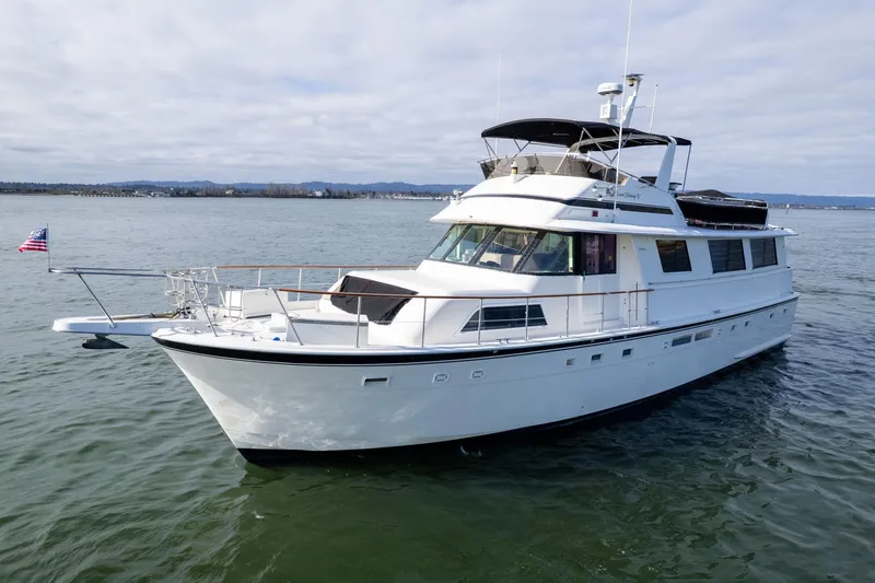 Slide: The Image of 1986 Hatteras 63 Motor Yacht cruising on calm waters under a cloudy sky. - 164