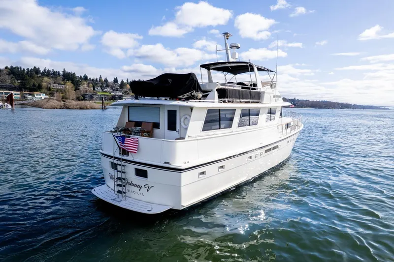 Slide: The Image of 1986 Hatteras 63 Motor Yacht cruising on a scenic waterway under a clear sky. - 165