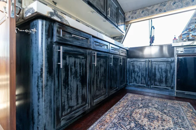 Slide: The Image of Interior of 1986 Hatteras 63 Motor Yacht with rustic kitchen cabinets and patterned rug. - 19