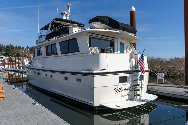 Slide: The Image of 1986 Hatteras 63 Motor Yacht docked, featuring sleek design and American flag. - 4
