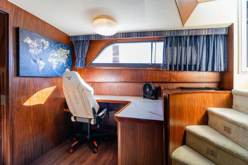 Slide: The Image of Interior of 1986 Hatteras 63 Motor Yacht with desk, gaming chair, and world map. - 49