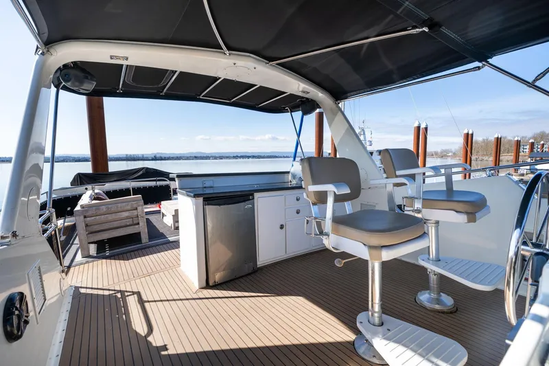 Slide: The Image of 1986 Hatteras 63 Motor Yacht deck with seating, helm, and scenic water view. - 75