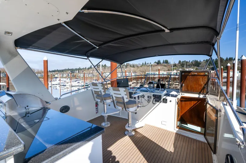 Slide: The Image of 1986 Hatteras 63 Motor Yacht helm with seating, canopy, and marina view. - 76