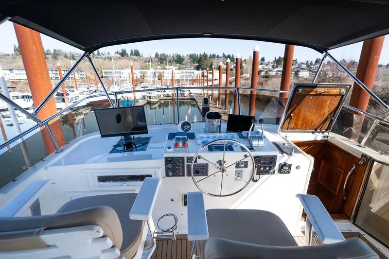 Slide: The Image of Helm of 1986 Hatteras 63 Motor Yacht with modern controls and marina view. - 81