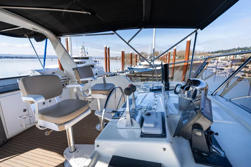 Slide: The Image of 1986 Hatteras 63 Motor Yacht helm with modern controls and seating, docked at marina. - 82