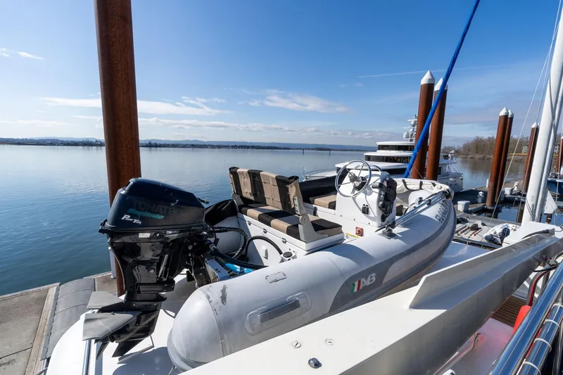Slide: The Image of 1986 Hatteras 63 Motor Yacht with inflatable boat and outboard motor docked by calm waters. - 94