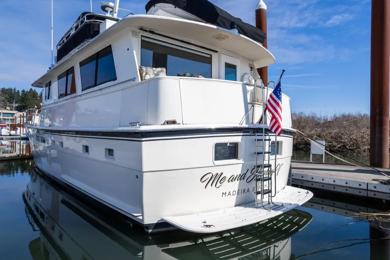 Slide: The Image of 1986 Hatteras 63 Motor Yacht docked, displaying American flag, clear sky background. - 95