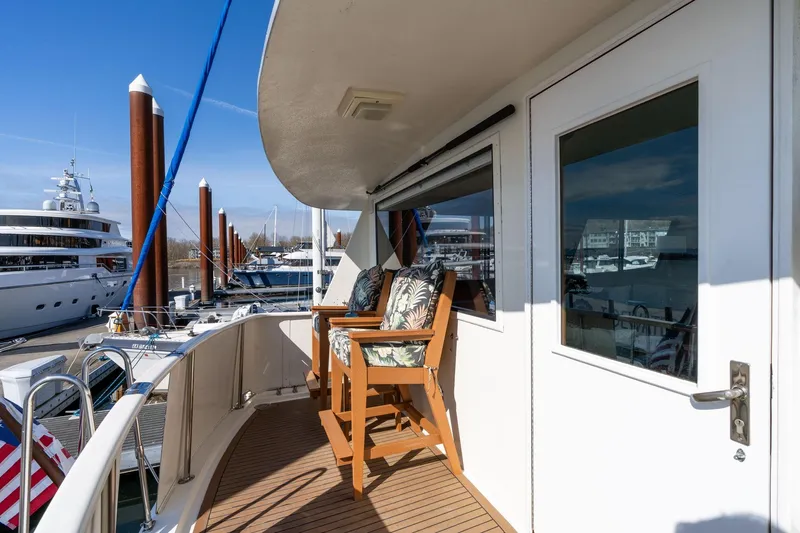 Slide: The Image of 1986 Hatteras 63 Motor Yacht deck with seating, docked at marina under clear blue sky. - 97