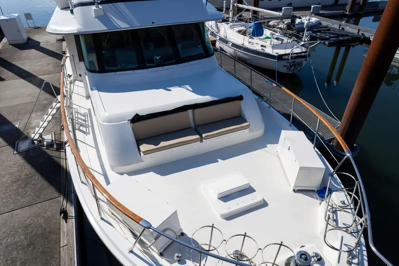 Slide: The Image of 1986 Hatteras 63 Motor Yacht docked, showcasing spacious deck and seating area. - 99