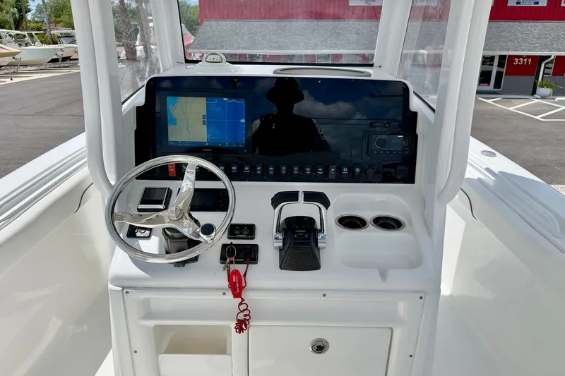 Slide: The Image of 2018 Sea Hunt Gamefish 27 helm with steering wheel, navigation display, and controls. - 17