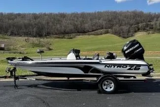 Slide: The Image of 2011 Nitro Z-6 boat with Mercury engine on trailer, parked outdoors. - 2