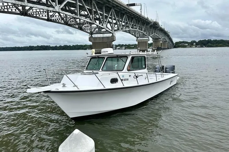Slide: The Image of 1989 C-Hawk 29 Sport Cabin boat under a large bridge on a cloudy day. - 2