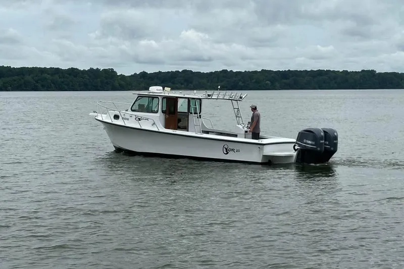 Slide: The Image of 1989 C-Hawk 29 Sport Cabin boat on calm water with dual outboard motors. - 3