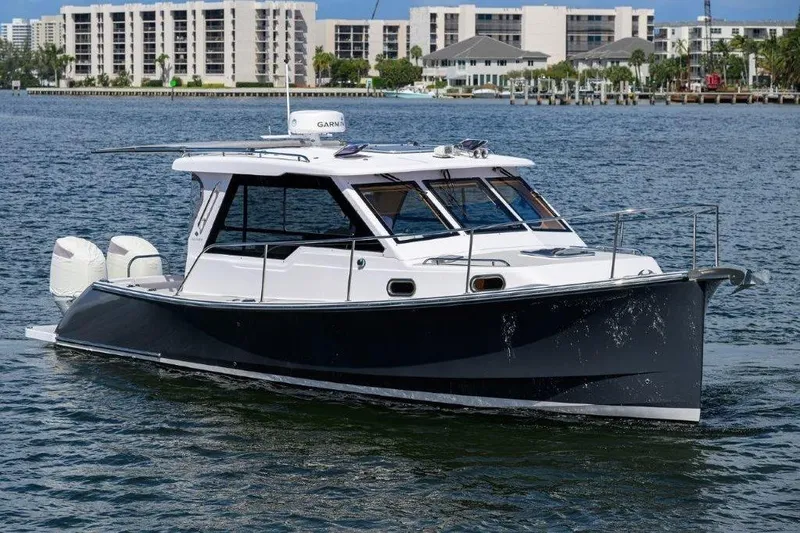 Slide: The Image of 2022 True North 34 boat cruising on water with modern buildings in the background. - 1