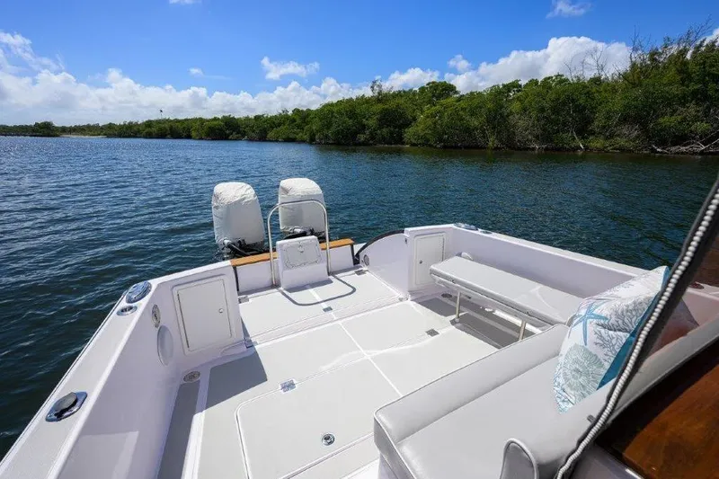 Slide: The Image of True North 34 boat deck, 2022 model, on calm water with lush greenery. - 11