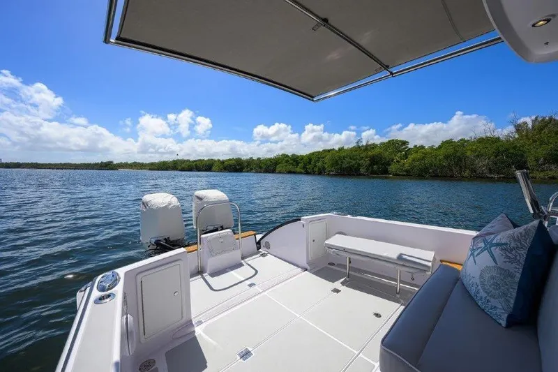 Slide: The Image of 2022 True North 34 boat deck with canopy, overlooking serene water and lush greenery. - 20