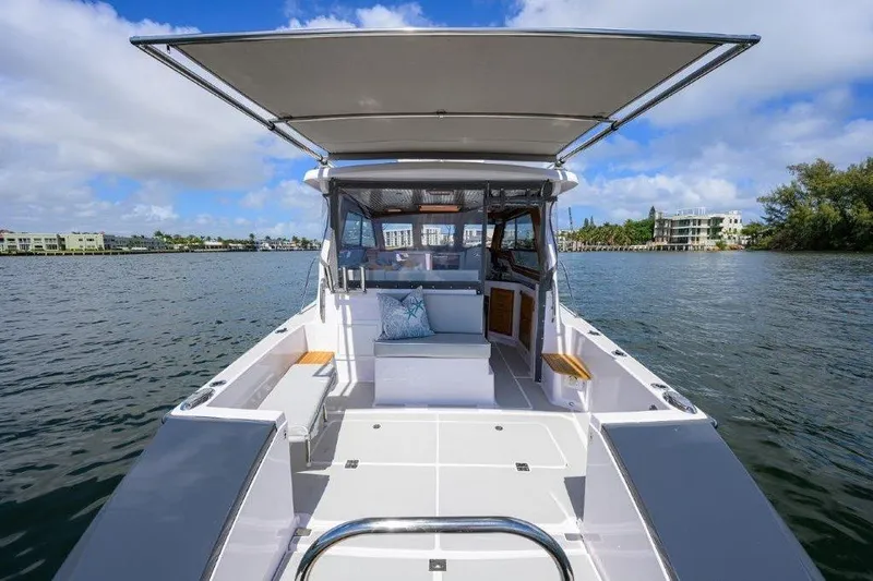 Slide: The Image of 2022 True North 34 boat on calm water, featuring spacious deck and canopy. - 23