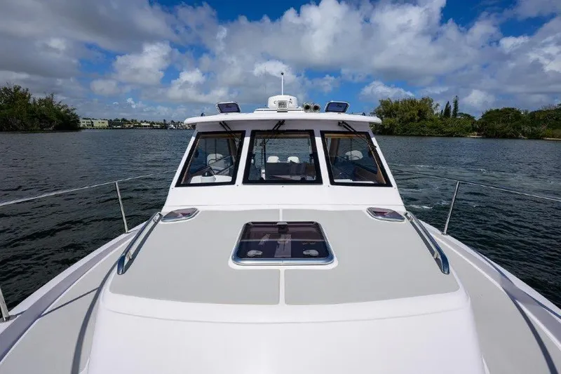 Slide: The Image of 2022 True North 34 boat cruising on a scenic waterway under a partly cloudy sky. - 41