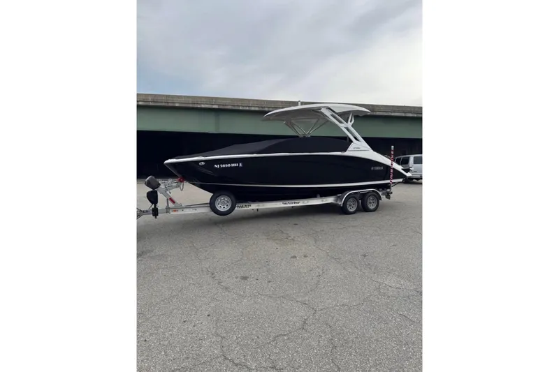 The Image of 2024 Yamaha Boats 275SD on trailer, sleek black design, parked outdoors. - 0
