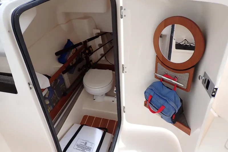 Slide: The Image of 2016 Grady-White Freedom 275 boat interior with toilet, fishing rods, and storage. - 8