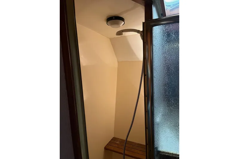 Slide: The Image of Shower area inside 1989 Egg Harbor 41 Convertible yacht with wooden bench and frosted glass door. - 13