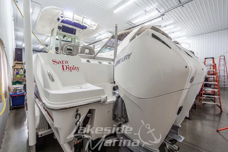 Slide: The Image of 2023 Boston Whaler 250 Outrage boat in a marina workshop, featuring dual Mercury engines. - 4