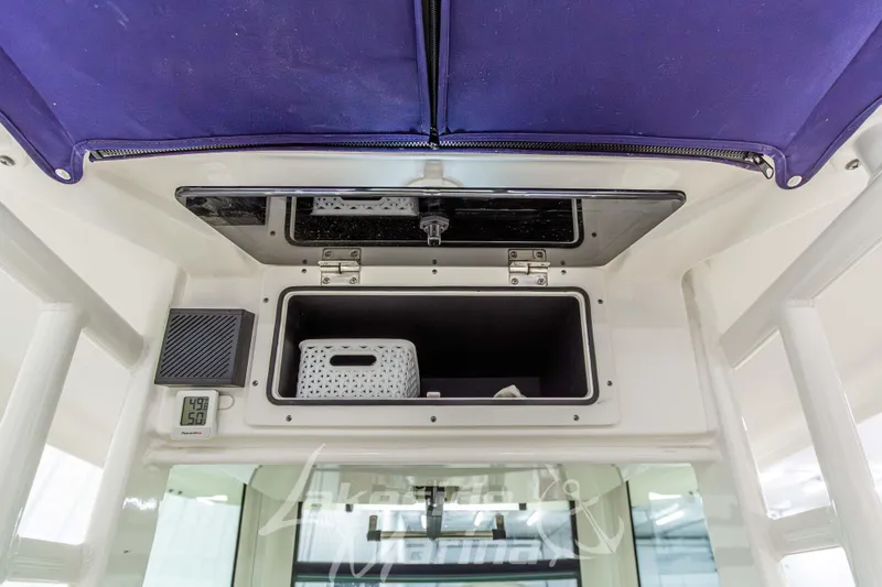 Slide: The Image of 2023 Boston Whaler 250 Outrage storage compartment with digital thermometer and purple canopy. - 44
