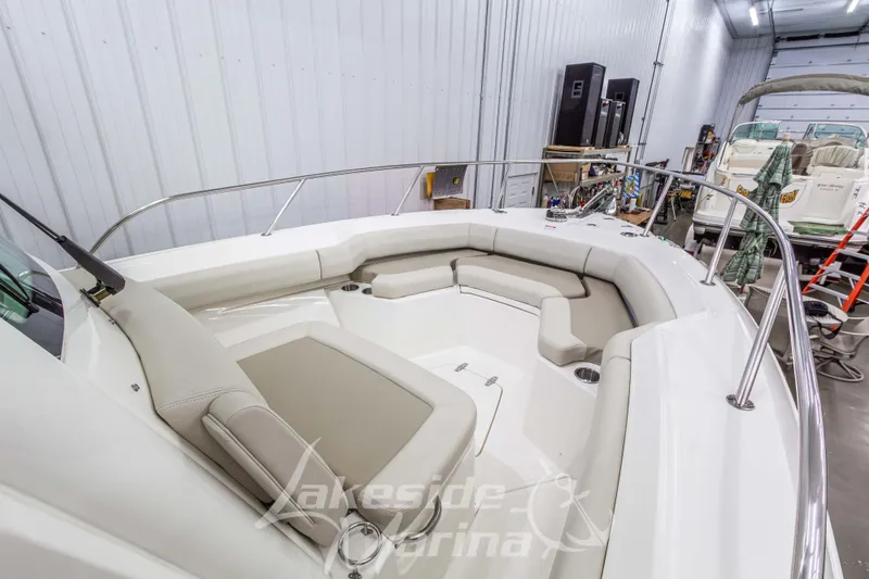 Slide: The Image of 2023 Boston Whaler 250 Outrage boat interior with cushioned seating in a marina setting. - 49