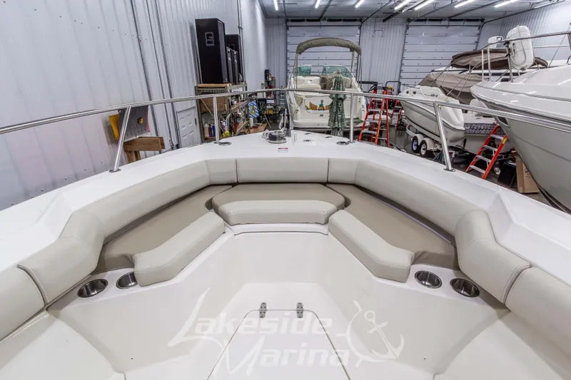 Slide: The Image of 2023 Boston Whaler 250 Outrage boat interior with cushioned seating in a marina setting. - 54