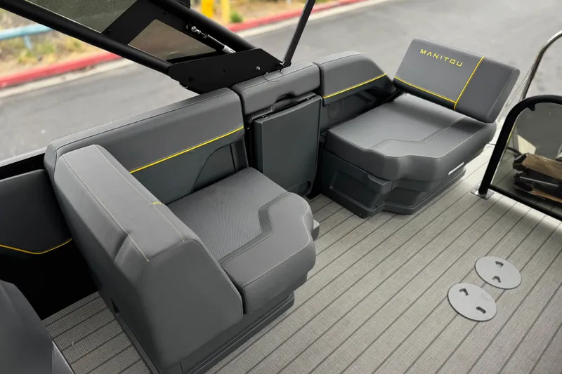 Slide: The Image of 2025 Manitou EXPLORE 24 boat interior with sleek gray seating and yellow accents. - 16
