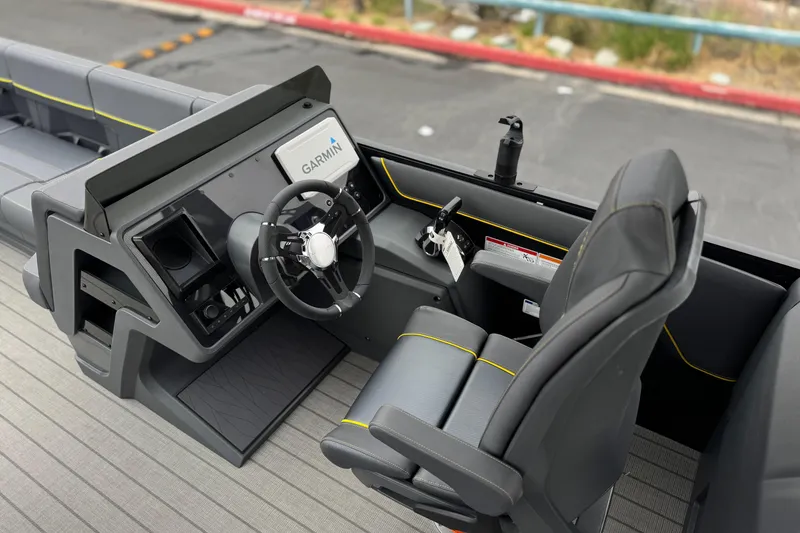 Slide: The Image of 2025 Manitou EXPLORE 24 boat cockpit with Garmin navigation system and sleek black seating. - 25