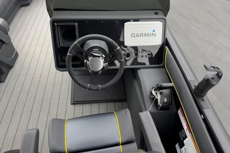 Slide: The Image of 2025 Manitou EXPLORE 24 boat dashboard with Garmin navigation system and sleek steering wheel. - 26