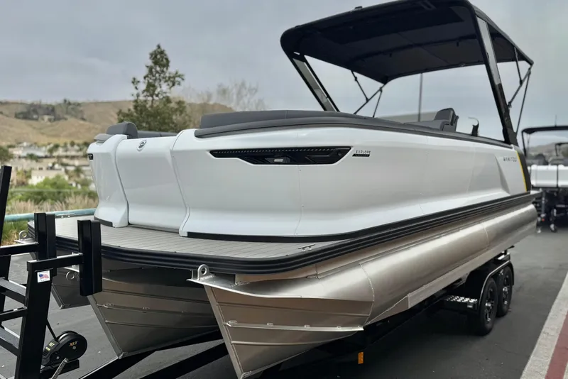 Slide: The Image of 2025 Manitou EXPLORE 24 pontoon boat on trailer, sleek design, outdoor setting. - 3