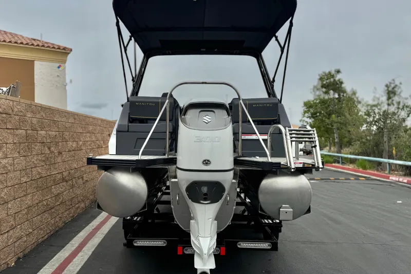 Slide: The Image of 2025 Manitou EXPLORE 24 boat with Suzuki 300 engine, parked outdoors. - 5