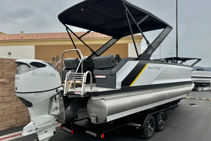 Slide: The Image of 2025 Manitou EXPLORE 24 pontoon boat with Suzuki engine, parked on a trailer. - 6