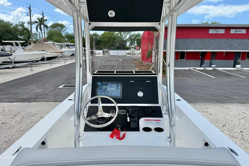 Slide: The Image of Bay Rider 2260 FS Skiff 2027 console with steering wheel and controls, parked outdoors. - 21