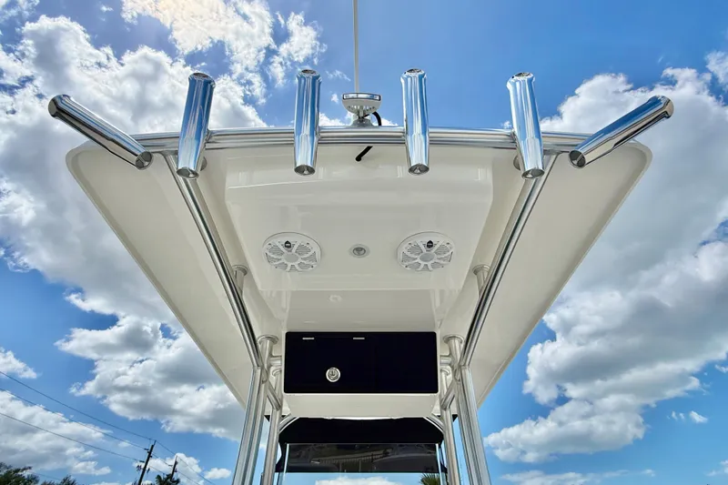 Slide: The Image of Bay Rider 2260 FS Skiff 2027 T-top with rod holders against a cloudy sky. - 48