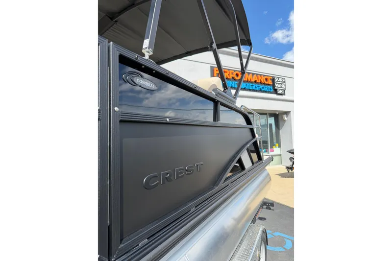 Slide: The Image of 2026 Crest Conquest 230 SLSC boat displayed outside a watersports store. - 11