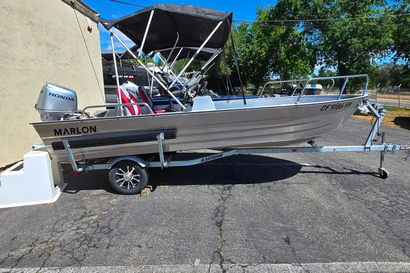 The Image of 2023 Marlon MV 16 boat on trailer with Honda motor, parked outdoors. - 1