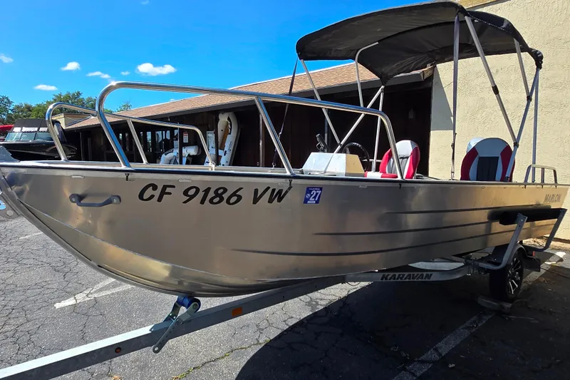 Slide: The Image of 2023 Marlon MV 16 boat on trailer, featuring sleek design and canopy, parked outdoors. - 2
