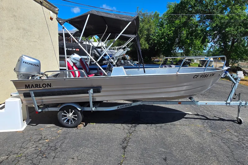 Slide: The Image of 2023 Marlon MV 16 boat on trailer with Honda motor, parked outdoors. - 8