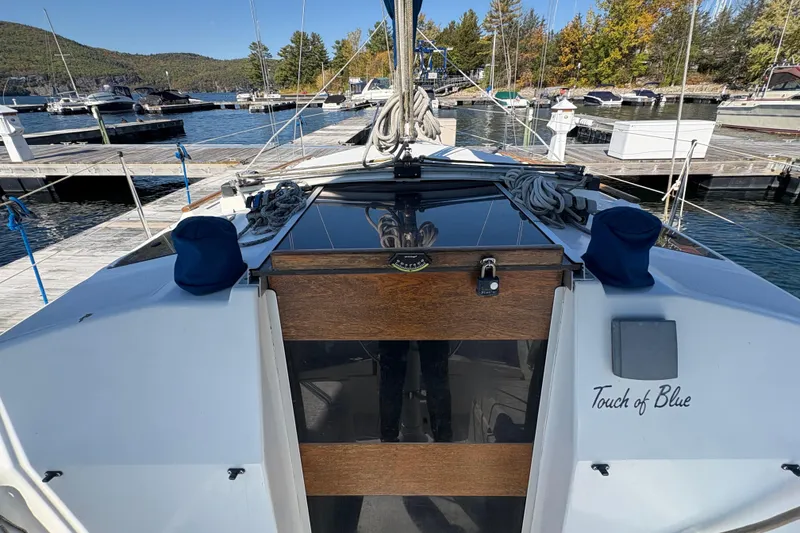 Slide: The Image of 1993 Hunter 28 sailboat "Touch of Blue" docked at a marina with scenic background. - 25