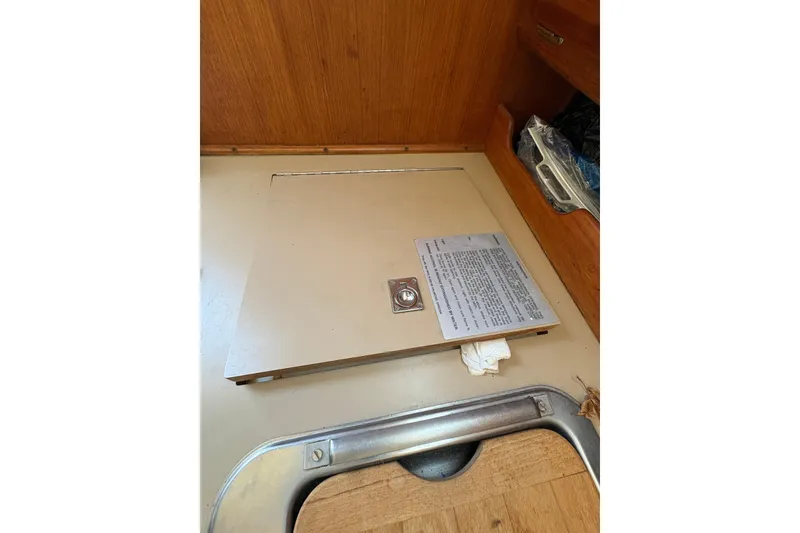 Slide: The Image of Floor hatch inside a 1993 Hunter 28 sailboat, featuring a metal latch and wooden interior. - 42