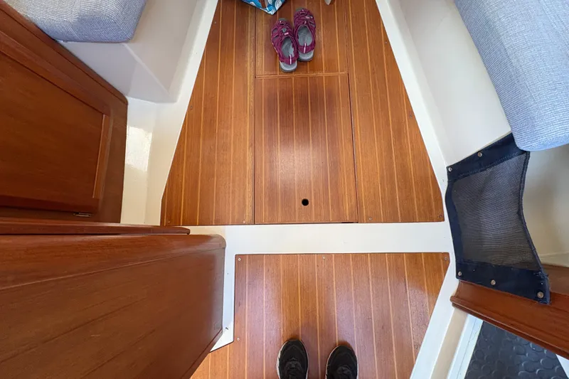 Slide: The Image of Interior view of a 1993 Hunter 28 sailboat with wooden flooring and visible shoes. - 54