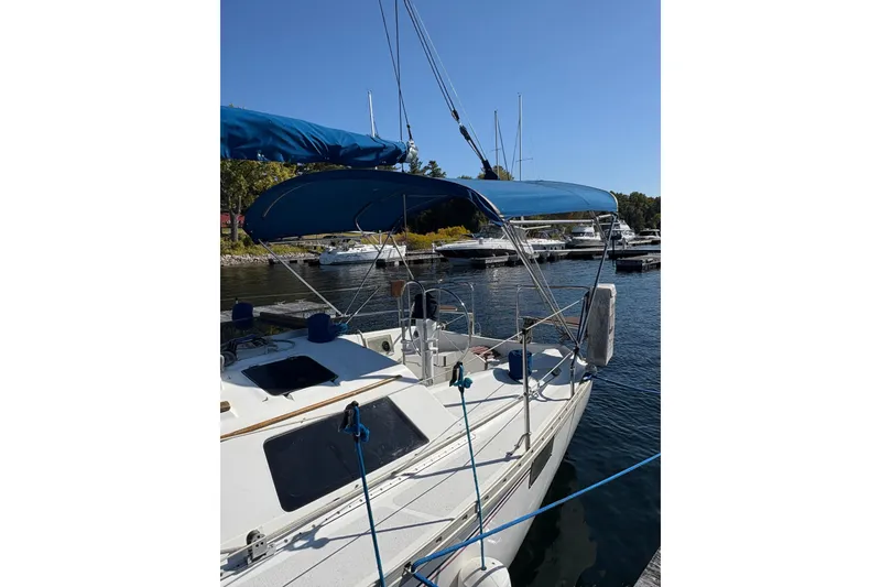 Slide: The Image of 1993 Hunter 28 sailboat docked at marina with blue canopy and clear sky. - 6