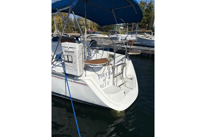 Slide: The Image of Hunter 28 sailboat from 1993 docked, featuring a blue canopy and "Touch of Blue" name. - 64