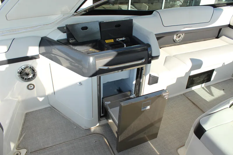 Slide: The Image of 2023 Formula 310 Bowrider I/O interior with open mini fridge and sleek seating. - 13