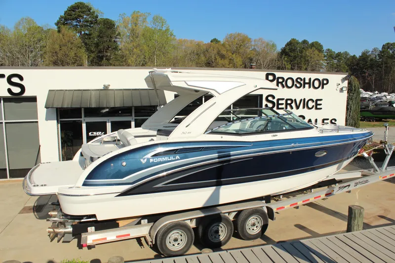 Slide: The Image of 2023 Formula 310 Bowrider I/O boat on trailer at dealership, sunny day. - 7